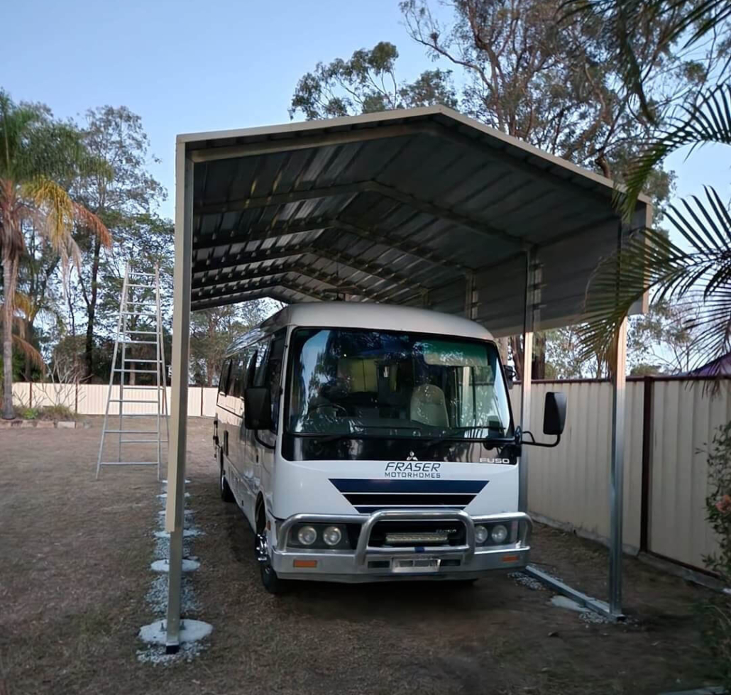 A caravan parked under a caravan shelter shed.