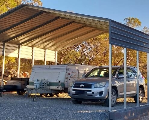 a car and trailer parked under a shade shed shelter