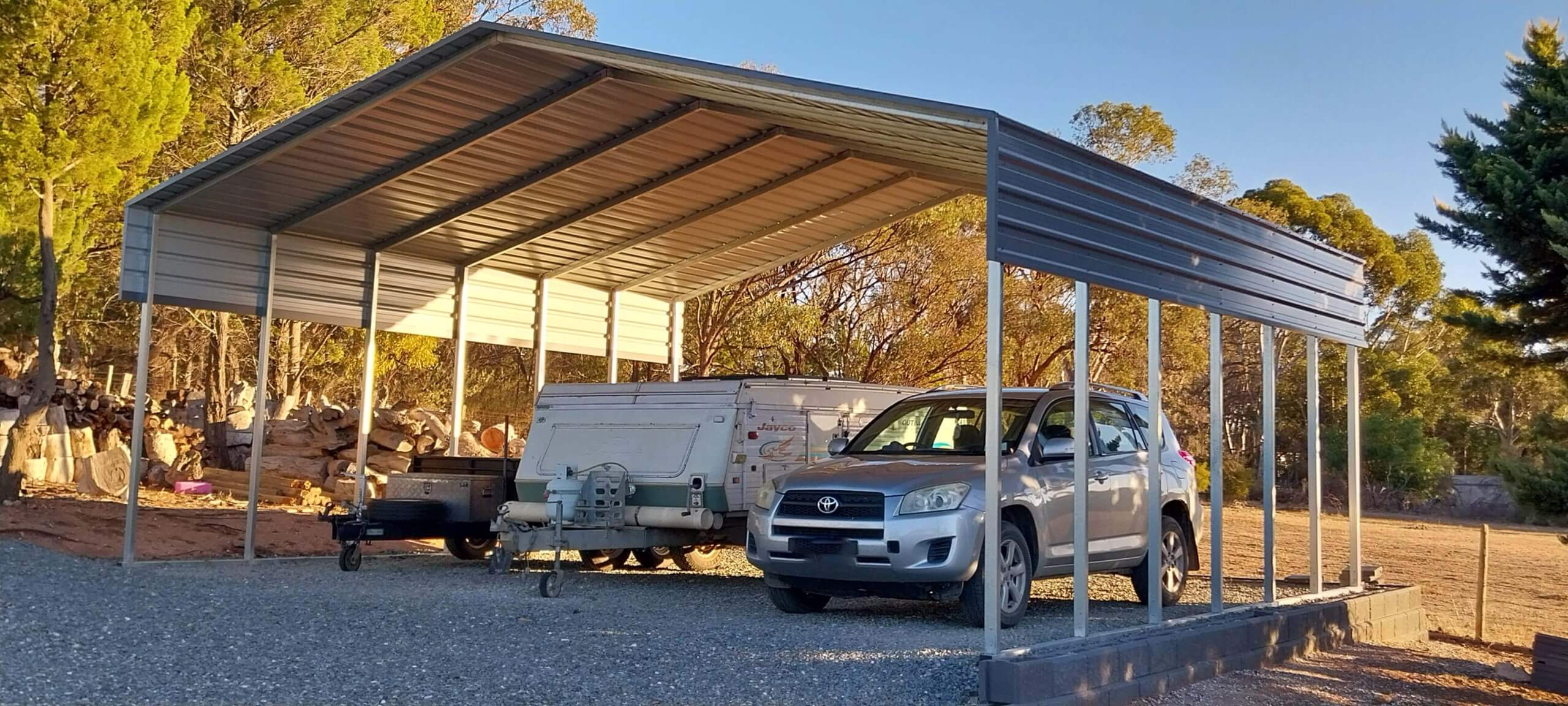 a car and trailer parked under a shade shed shelter